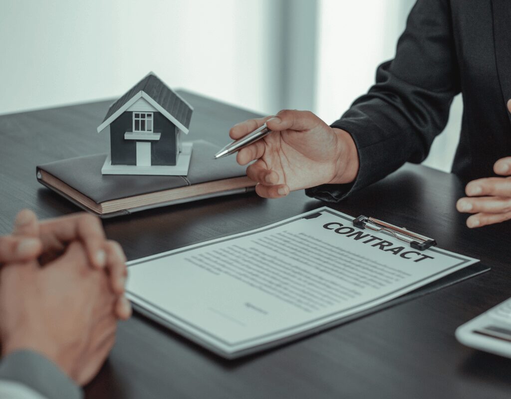 a person holding a pen over a house model