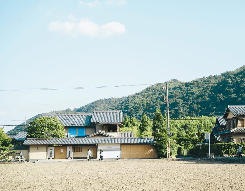 a house with a large field and trees in the background in countryside of Japan