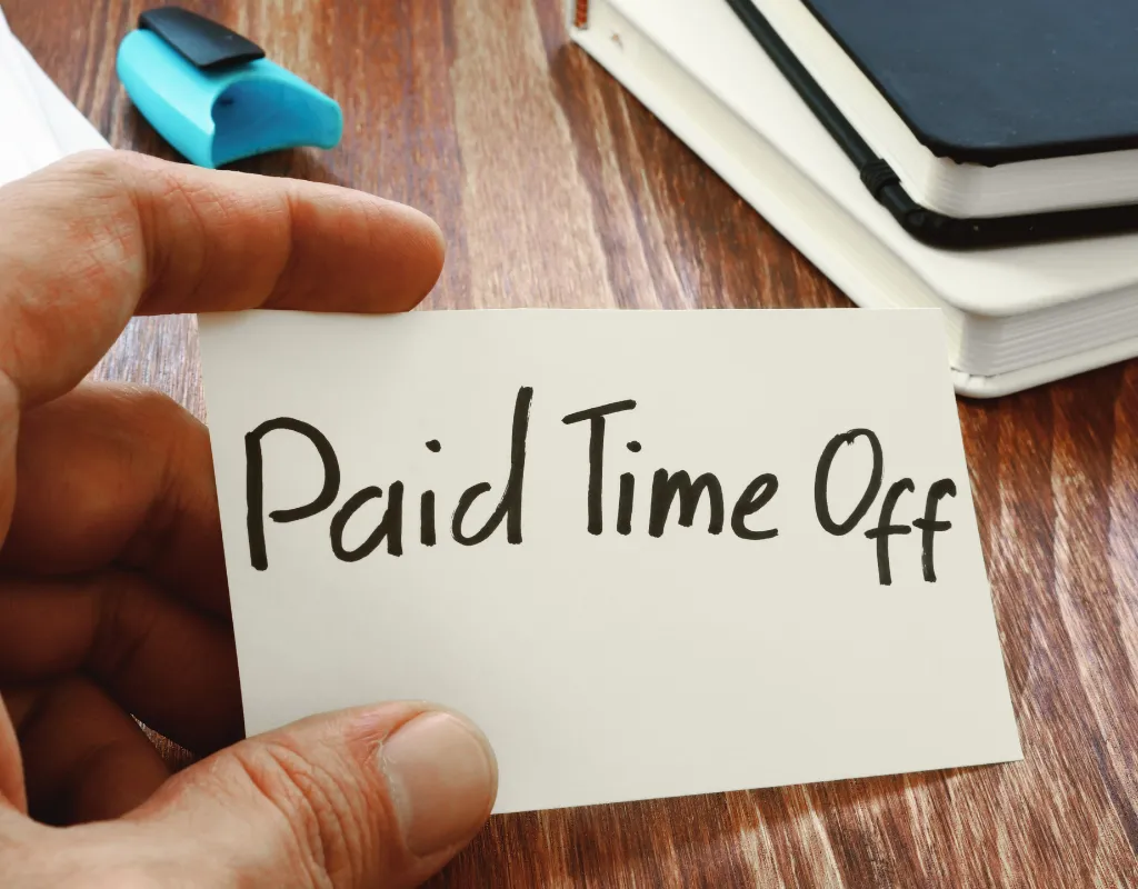 a hand holding a sign with text, paid time off