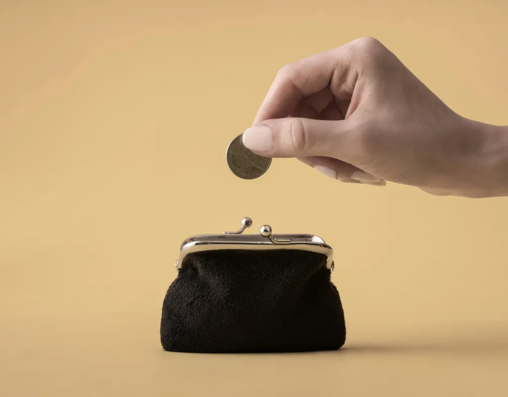 a hand putting a coin into a small black purse