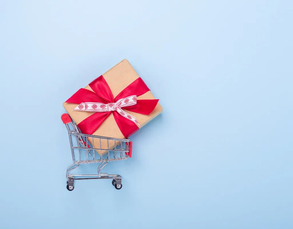 a gift wrapped in a red ribbon in a shopping cart